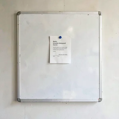 Empty whiteboard wall with a single faint pinned card on a chalk surface