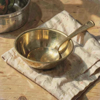 Warm hero of a brushed brass dinner spoon resting on a folded oat linen, late af