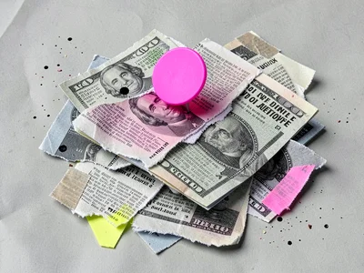 Clipped pile of paper money torn into rough quarters carries one fluorescent pin