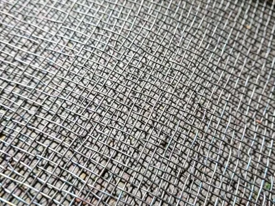Woven wire cloth, fine mesh like metal fabric, tight grid creating moiré at slig