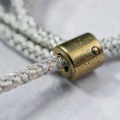 Tight mineral close-up of a braided fabric power cord meeting a brass collar