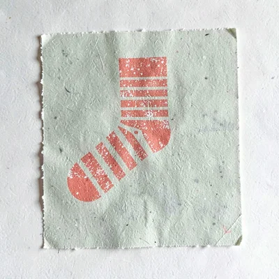 Two-color riso of a halftone striped sock motif in coral over a sage paper field