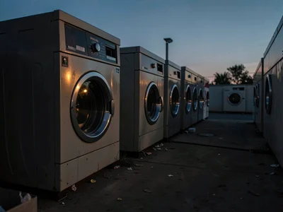 Laundromat at dusk, last loads spinning, week's preparation in progress