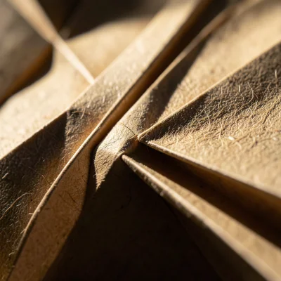 Extreme macro of an origami crane wing tip, layered paper edges visible at the p