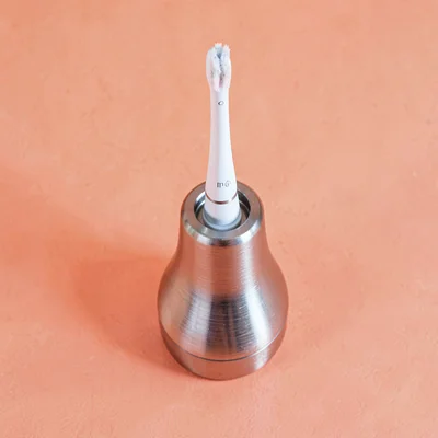 single brushed-aluminium electric-toothbrush charger-stand top-down on a saturat