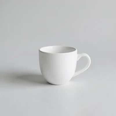 A minimalist studio photograph of a single white coffee cup on a plain neutral background, clean composition with lots o
