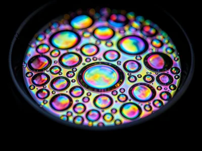 Oil on water in a shallow black dish, complete darkness below making interferenc