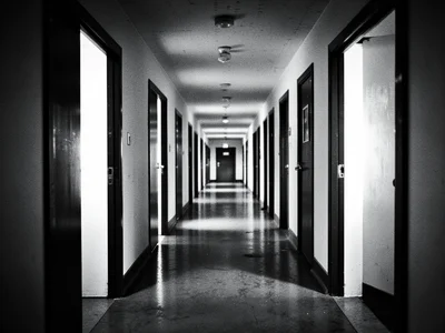 A row of identical doorways in a long corridor, each framing a rectangle of ligh