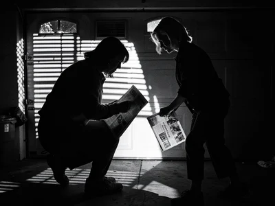 Soccer mom silhouette against garage door light, mysterious figure picking up ne