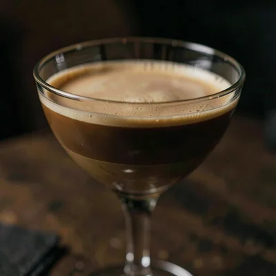 Moody close-up of a glass of espresso martini with a perfect crema, low single l