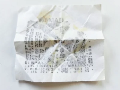 Receipt crumpled and partially smoothed, crinkle texture overlaid on fading prin