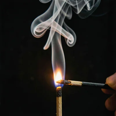 A match just struck, igniting — combustion gases swirling upward in dense waveri