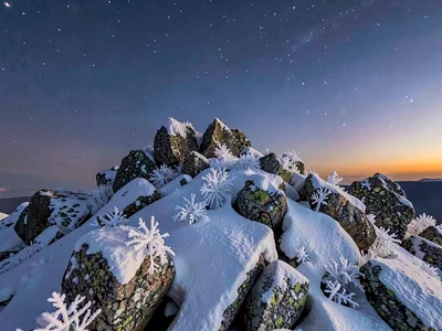 Frost crystals on summit rocks under twilight-to-space gradient
