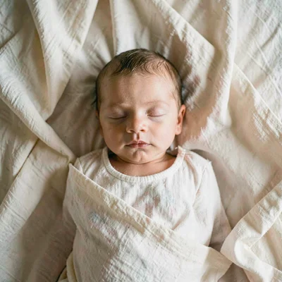 Top-down portrait of a sleeping newborn on a bed of muslin folds