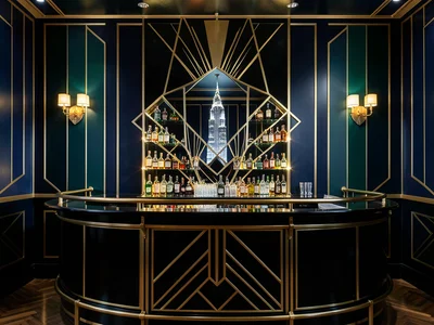 A cocktail bar in the Deco style: curved black lacquer counter, brass rail, back