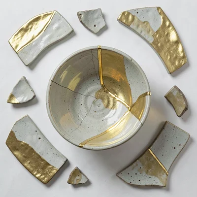 Overhead flat-lay of ceramic shards arranged around repaired bowl — reconstructi