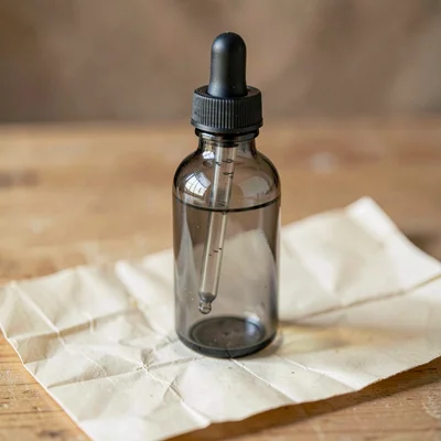 squat apothecary tincture dropper bottle in smoke-grey glass with a black rubber