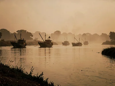 Fishing boats on river as dark forms in amber