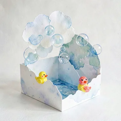 A pop-up paper bath time with torn-paper bubble cloud and crayon rubber ducks