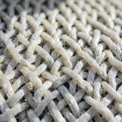 Mineral-cut close-up of a wool weave with raised threads catching raking light