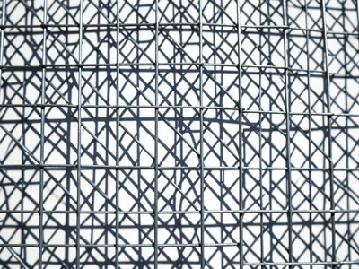 Wire mesh shadow on white wall, sunlight projecting the grid pattern as crisp ge
