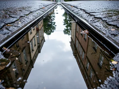 Puddle between railroad tracks reflecting converging rail lines above, parallel 
