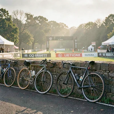 Atmospheric race-day scene of bicycles leaning against a stone wall before a sta