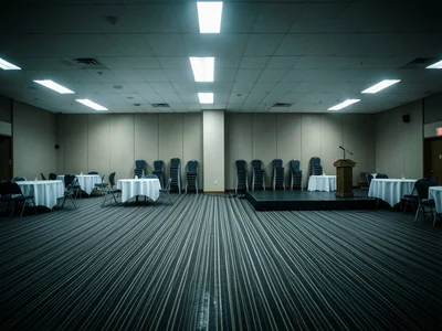 A hotel banquet hall being set up for an event, round tables with white tableclo