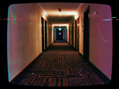A hotel hallway stretching into darkness, the carpet pattern disrupted by scan l