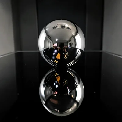 Mercury-like liquid chrome sphere floating above reflective black surface, disto