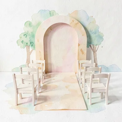 Papercraft layout of a tiny paper venue scene with paper arch, paper aisle, and 