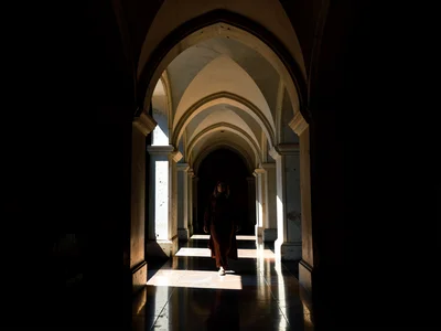 Long arcaded corridor where every other arch holds darkness and every alternate 