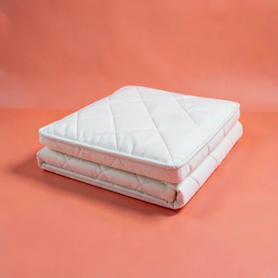Catalog hero of a folded mattress topper centered on a saturated coral backdrop,