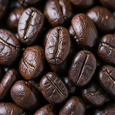 Studio macro top-down of a tight cluster of dark-roast beans, fissures and gloss