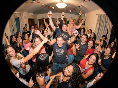 House party at peak chaos, fisheye capturing entire room of dancing bodies warpe