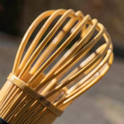 Tight crop of a bamboo whisk's split tines, hard side light catching the splay