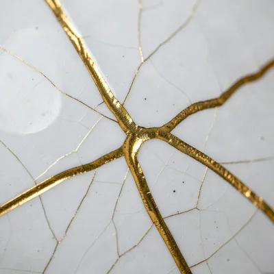 Abstract detail of gold crack seam on white glaze — macro, fine crack branches