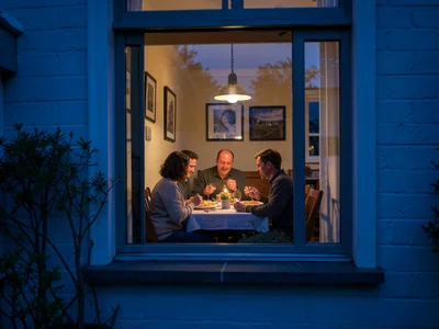 Shot from outside a house during blue hour, looking through a window at a family