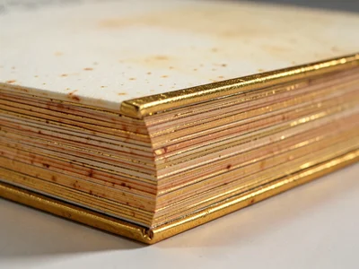 Gilded book edge, gold leaf application on page edges creating warm metallic sur