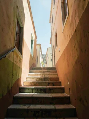 Mid-morning staircase climbing into a slot of bright sky, lower steps still cool