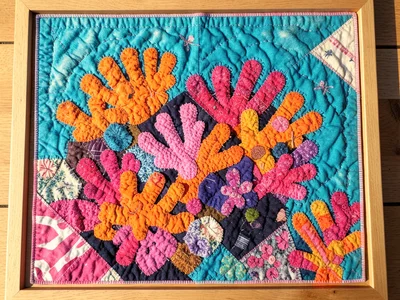 A coral reef from above in brilliant orange, pink, and purple fabric pieces in t