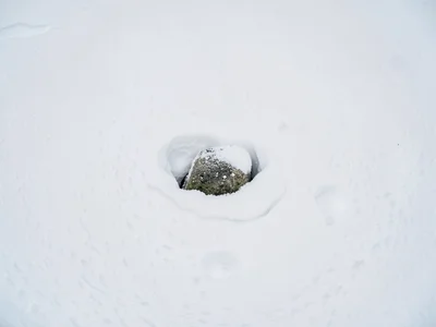 Single stone emerging from snow drift