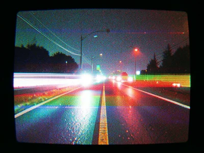 A highway at night, headlights smearing into horizontal bands of white and red