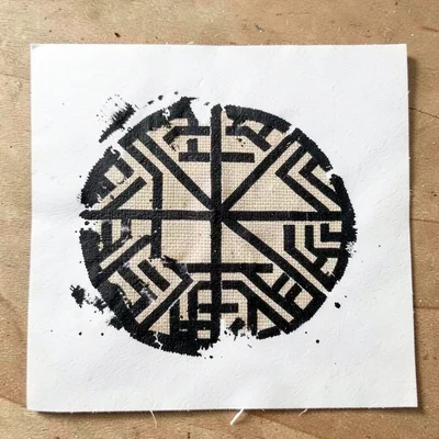 Symbol rubbing on paper — wet impression of single stamp transferred to white gr