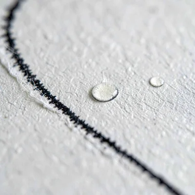 Mineral close-up of a wet ink line on heavy paper, soft fiber bloom along the ed