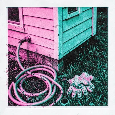Vinyl-sided corner of a house with a coiled garden hose and a pair of muddy gard