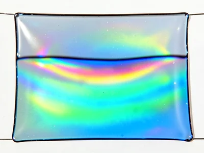 Soap film stretched across wide rectangular frame, gravity pulling thin at top c