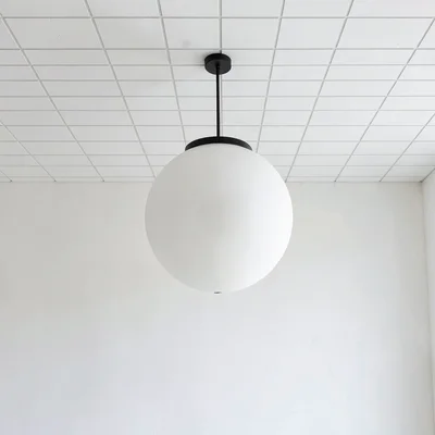 Spherical pendant light against white ceiling grid, minimal shadow