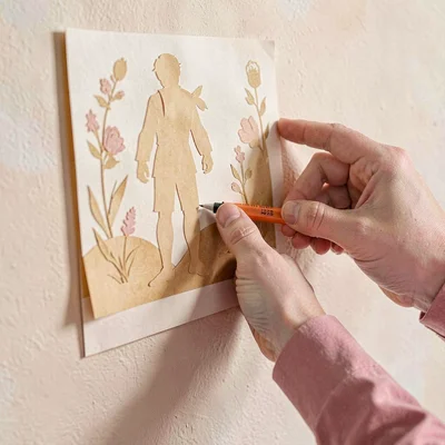 Papercraft hero of a layered paper-cut hand pinning a poster to a wall, warm hon