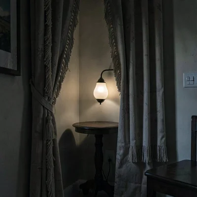 Quiet alcove with a tasselled curtain pulled half open, soft sconce glow on a sm
